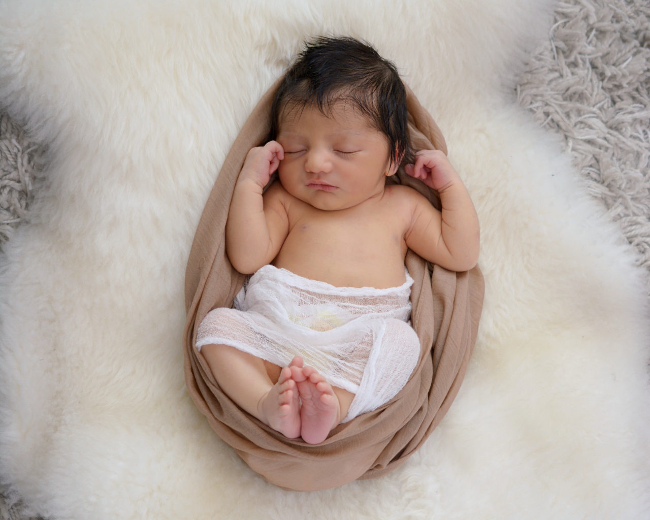 Спящий грудной ребенок на меховом покрывале 