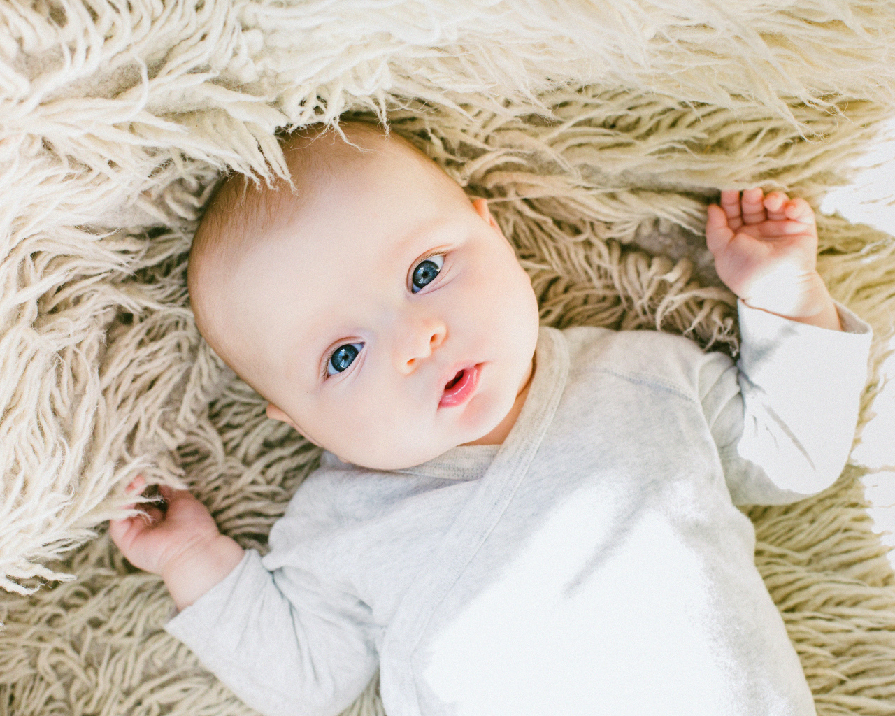 Маленький грудной ребенок на меховом покрывале 