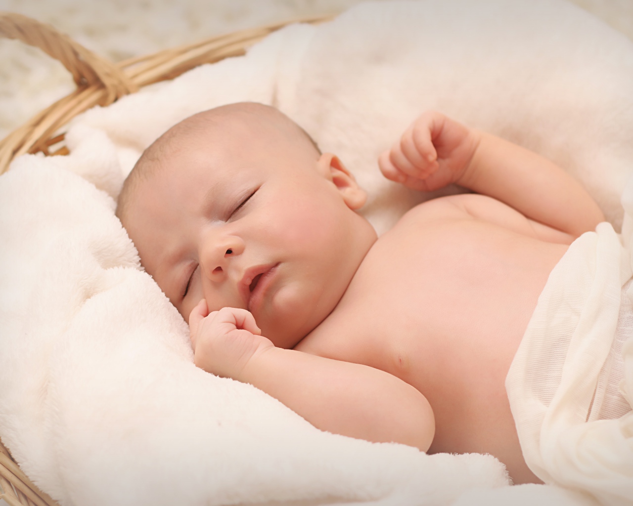Маленький грудной ребенок спит в корзине 