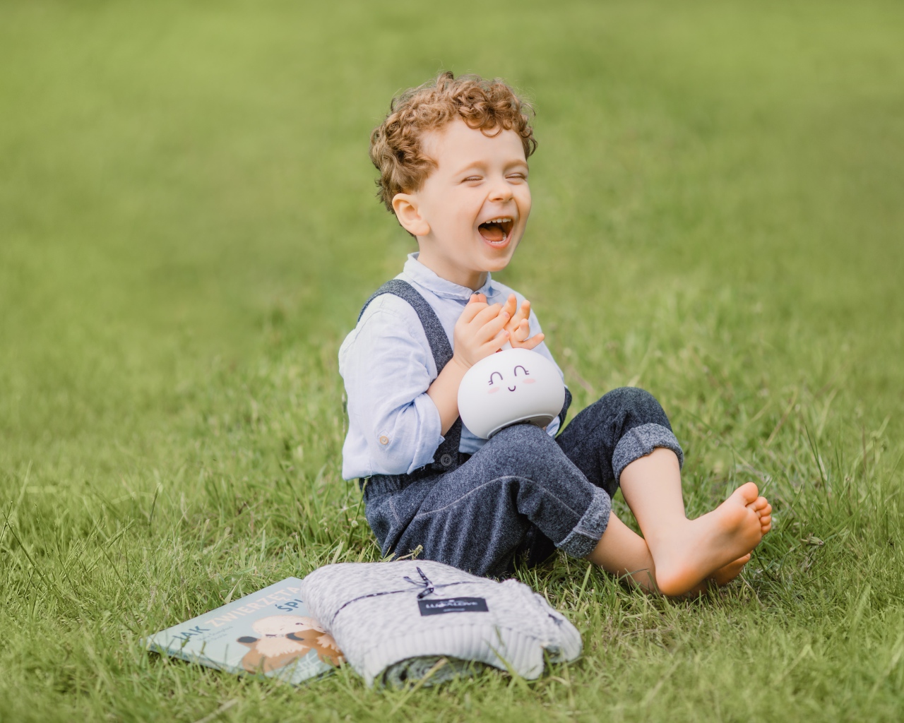 Улыбающийся мальчик сидит на траве