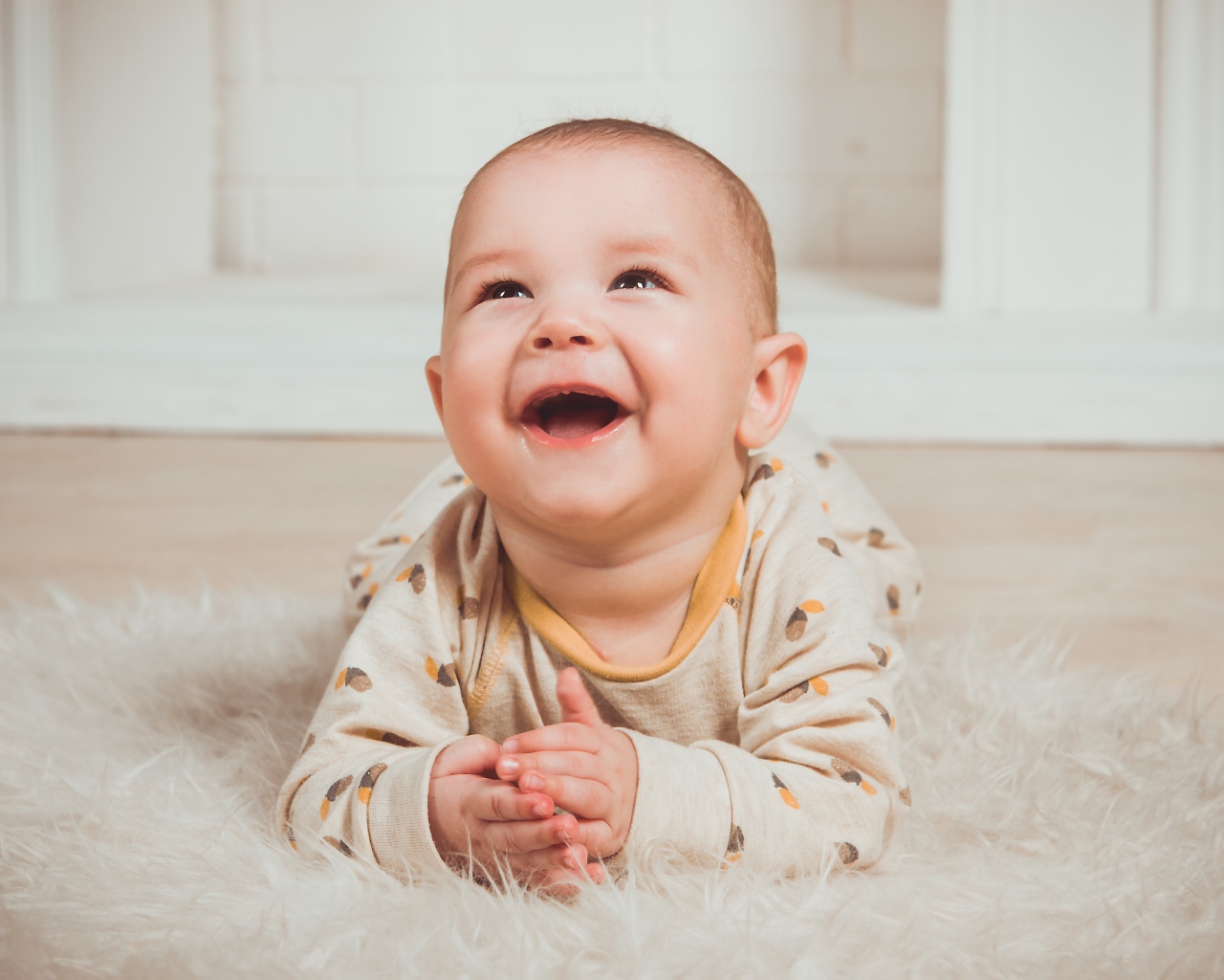 Улыбающийся грудной ребенок лежит на меховом покрывале 