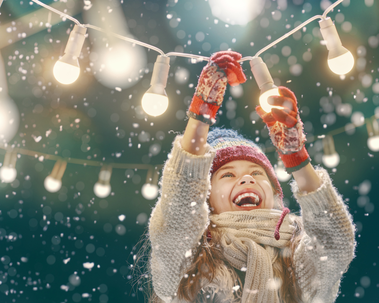 Улыбающаяся девочка вешает лампочки 