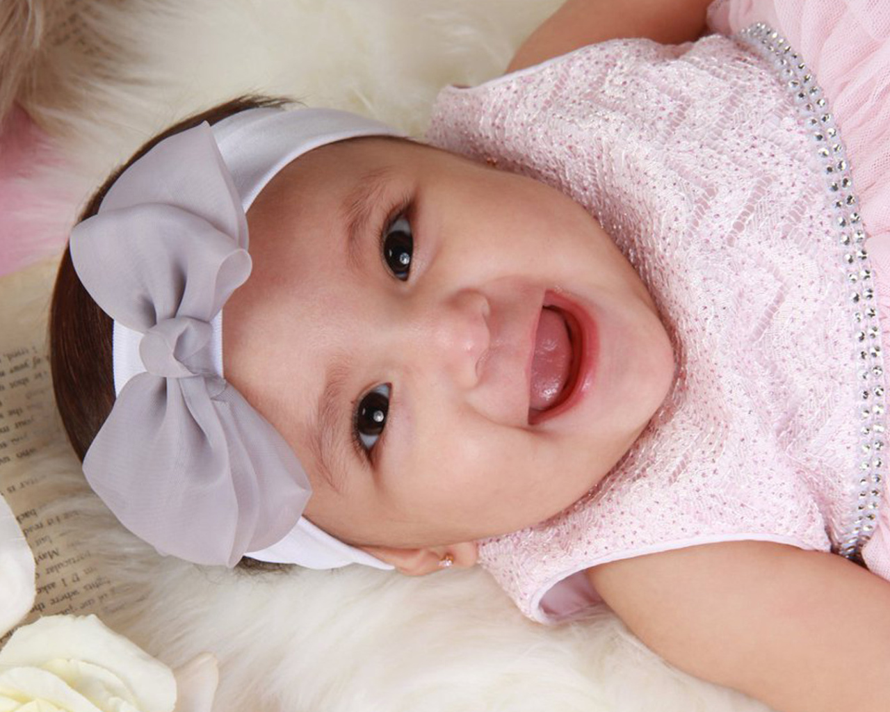 Улыбающаяся девочка в розовом платье с бантом на голове