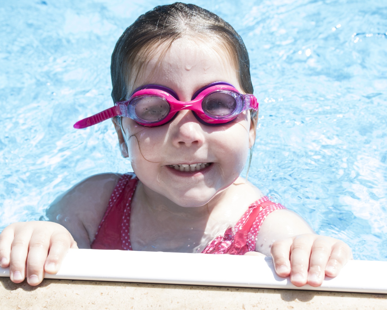 Улыбающаяся девочка в очках в бассейне