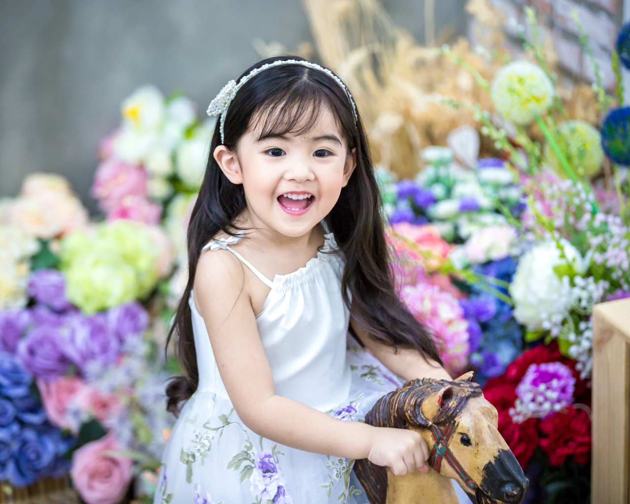 Улыбающаяся маленькая девочка азиатка на лошадке