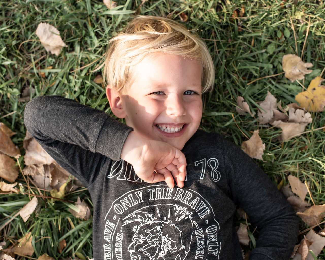 Улыбающийся маленький мальчик лежит на траве