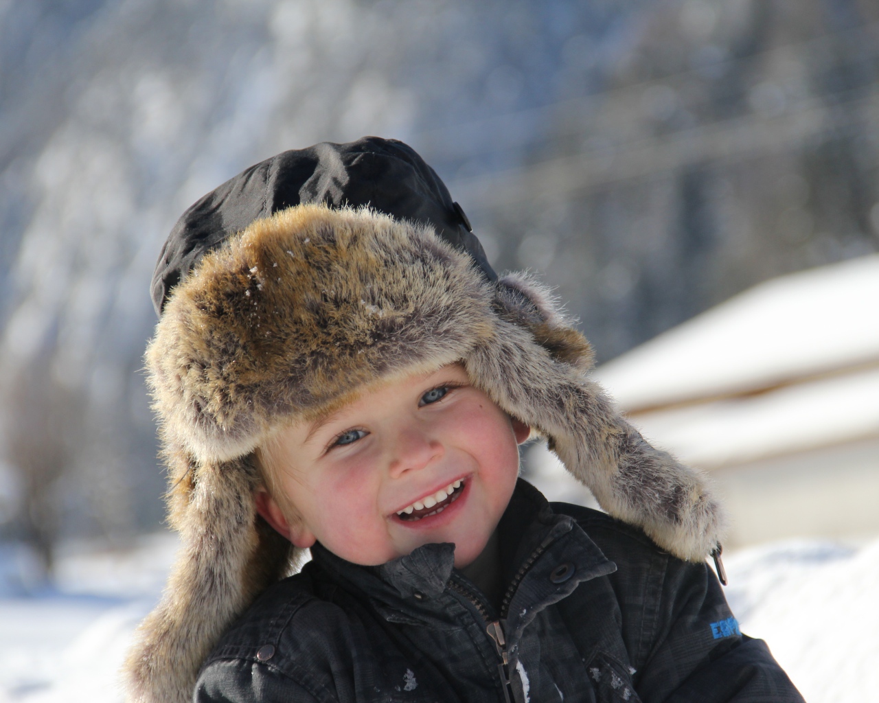 Улыбающийся  маленький мальчик в зимней шапке 