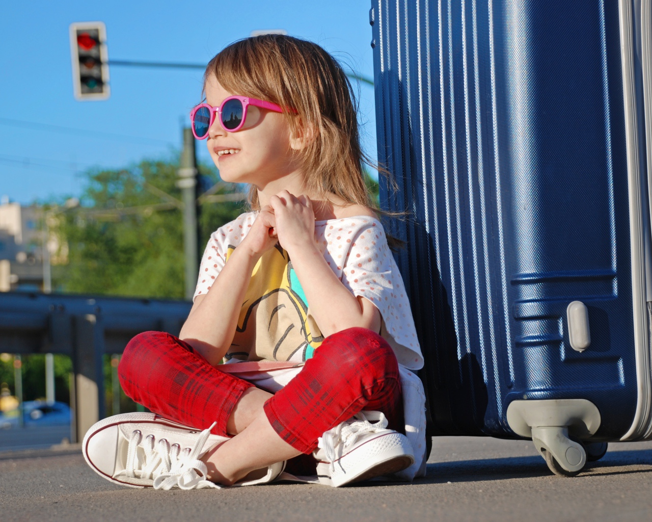 Улыбающаяся маленькая девочка в очках с чемоданом