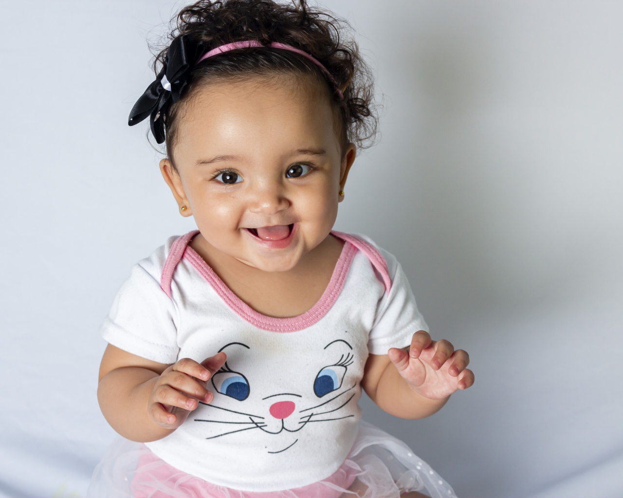 Улыбающаяся маленькая девочка на сером фоне 