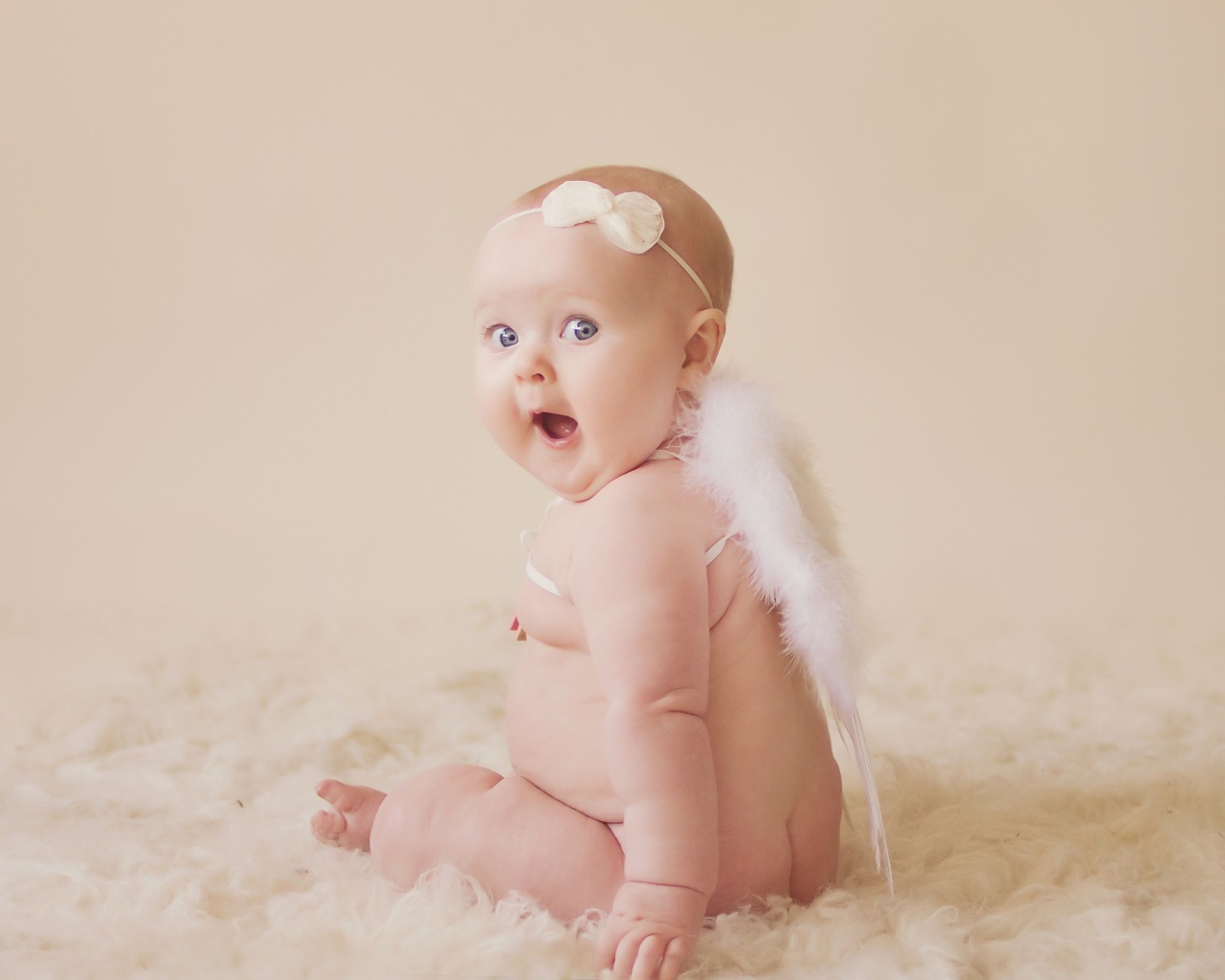 Удивленный грудной ребенок с белыми крыльями за спиной 