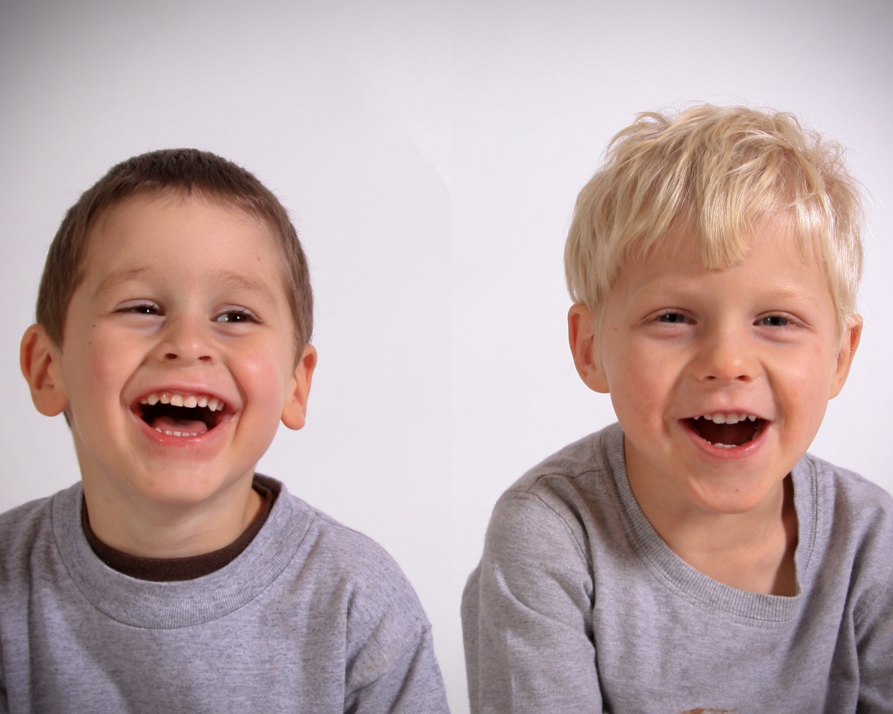 Два маленьких мальчика смеются на сером фоне
