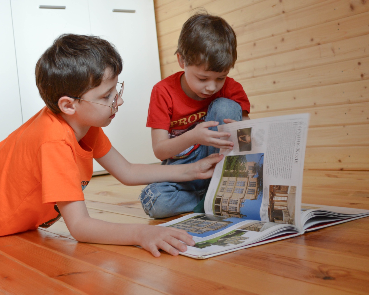 Два маленьких мальчика с книгой  на полу