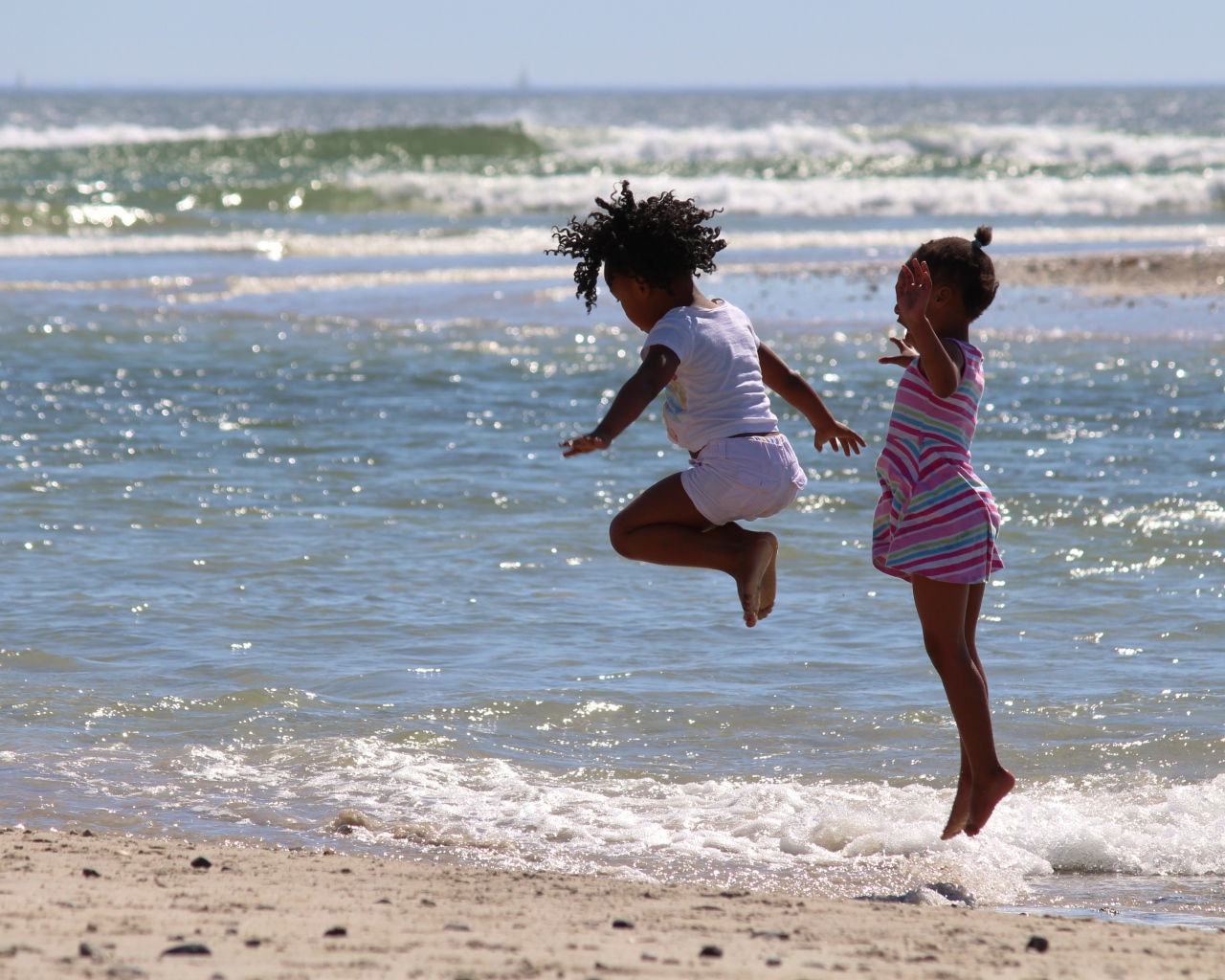 Две маленькие девочки играют на морском берегу