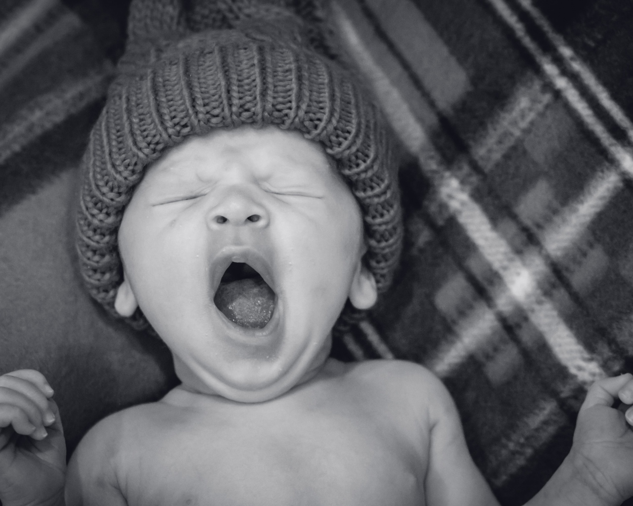 Зевающий ребенок в теплой шапке 