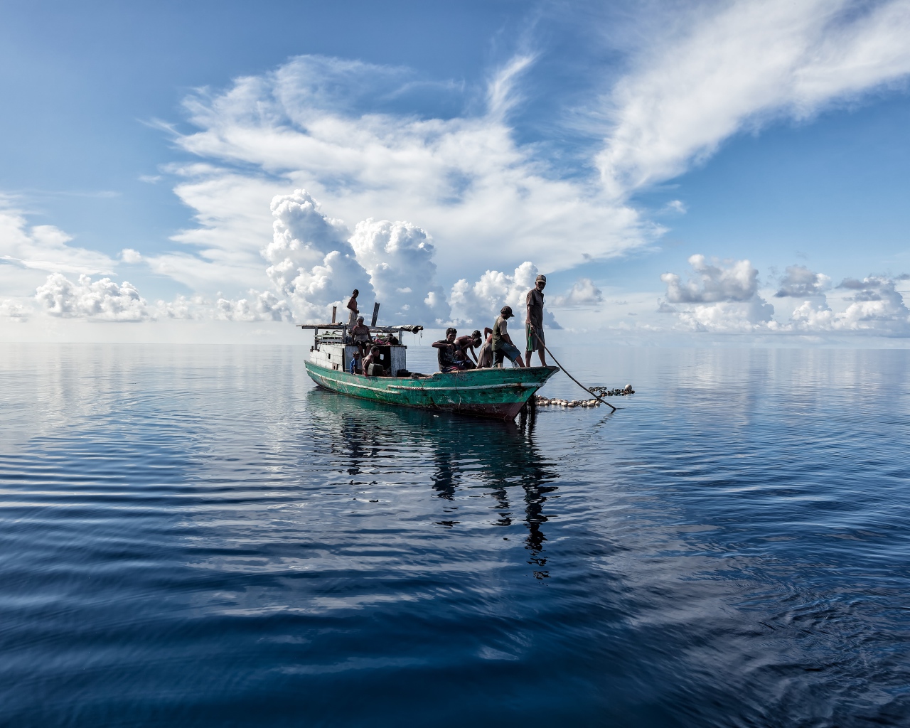 Boat with fishermen at sea with white clouds
