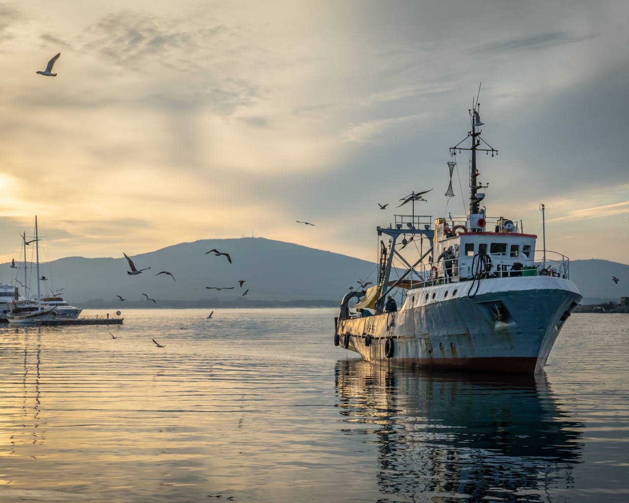 Старое рыболовное судно в море на закате 