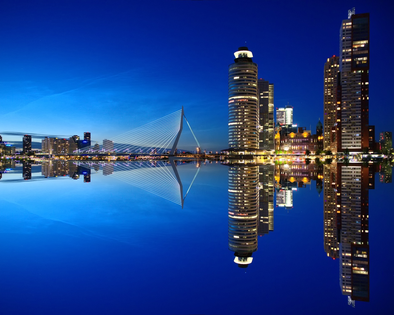 Skyscrapers and bridge are reflected in calm water
