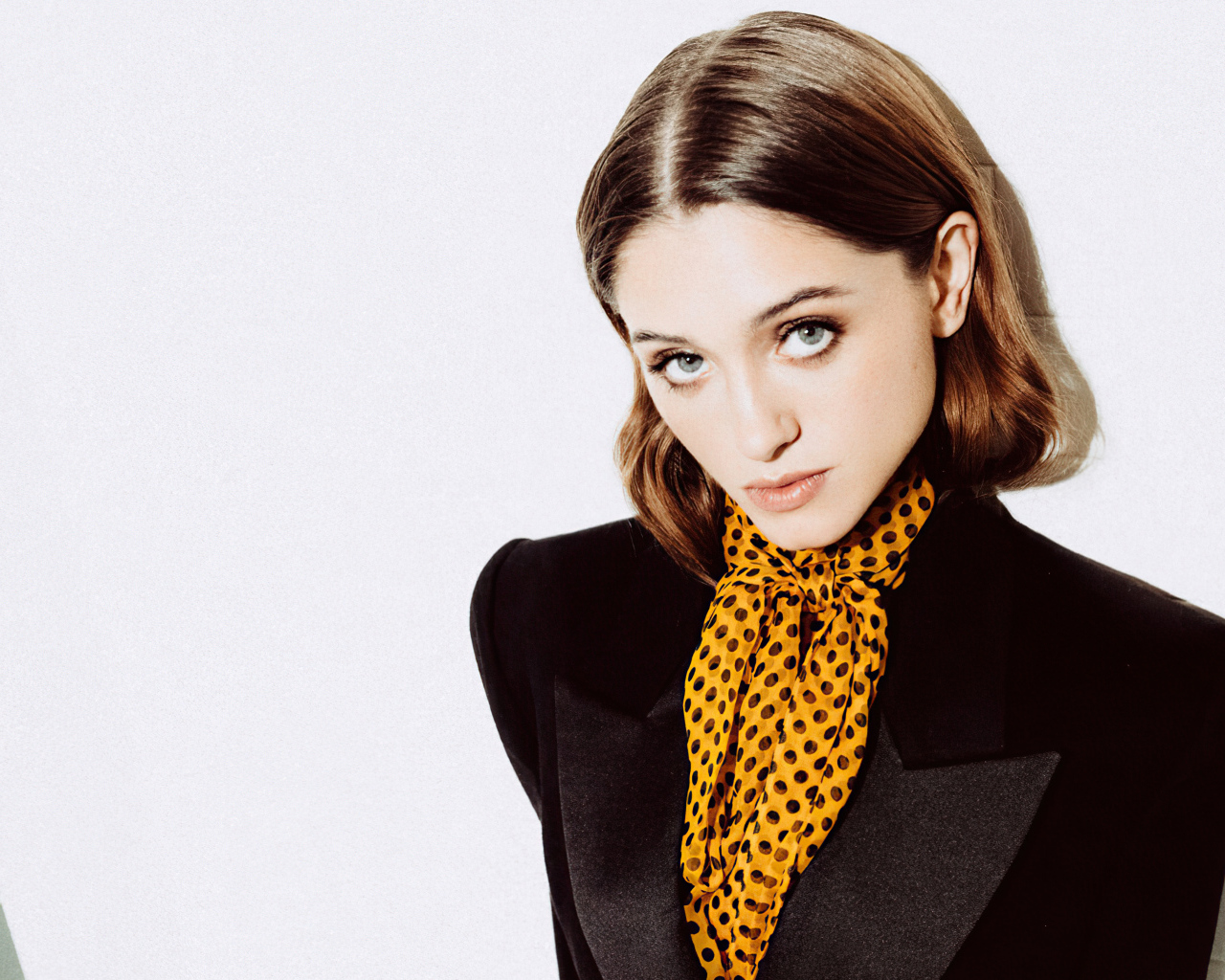 Актриса Наталия Дайер в черном пиджаке на белом фоне