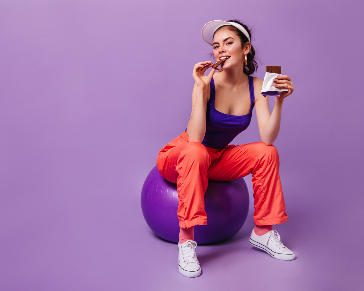 Девушка с шоколадкой сидит на фитболе
