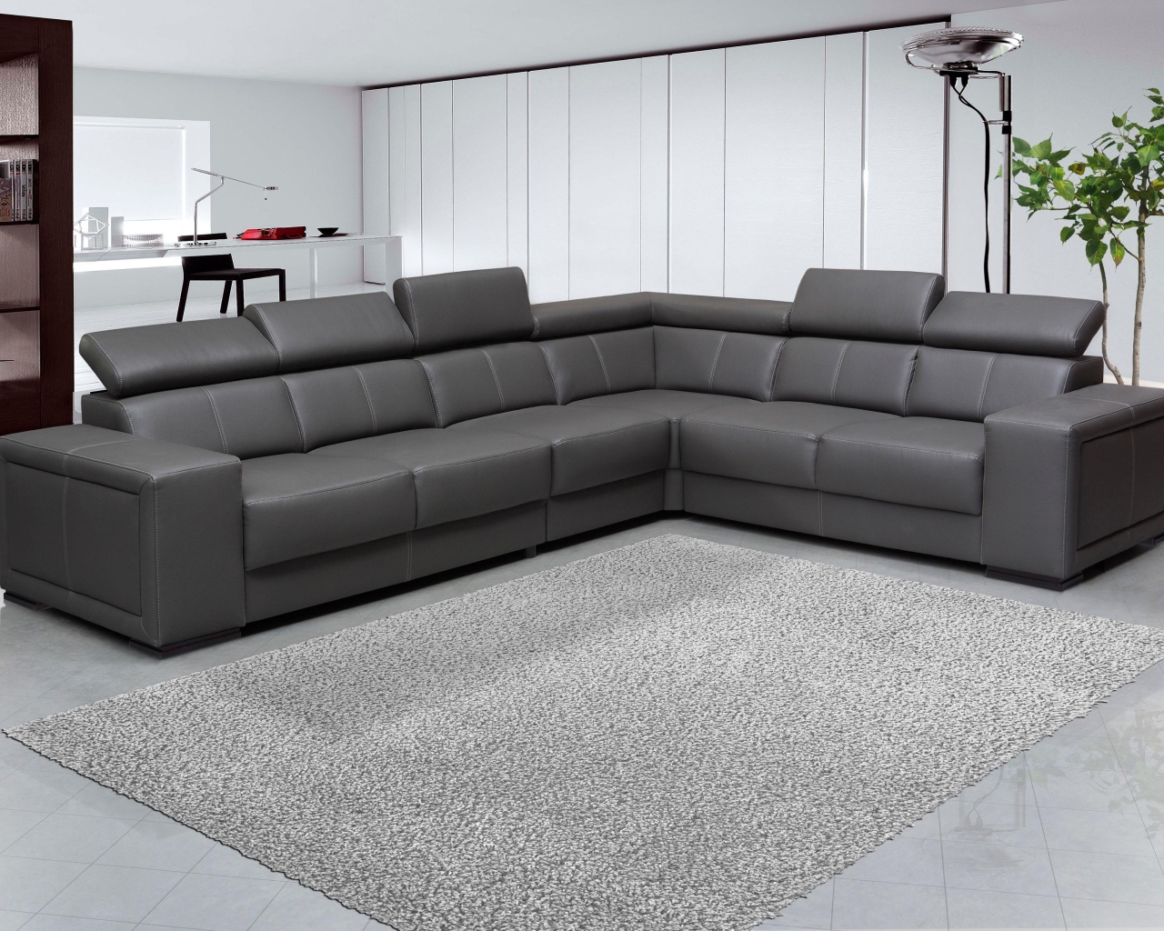 Большой черный угловой диван в комнате с белыми стенами