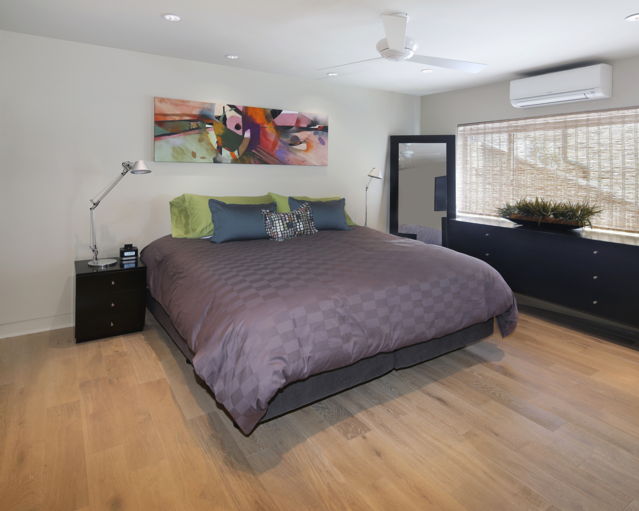 Большая серая кровать в спальне с белыми стенами