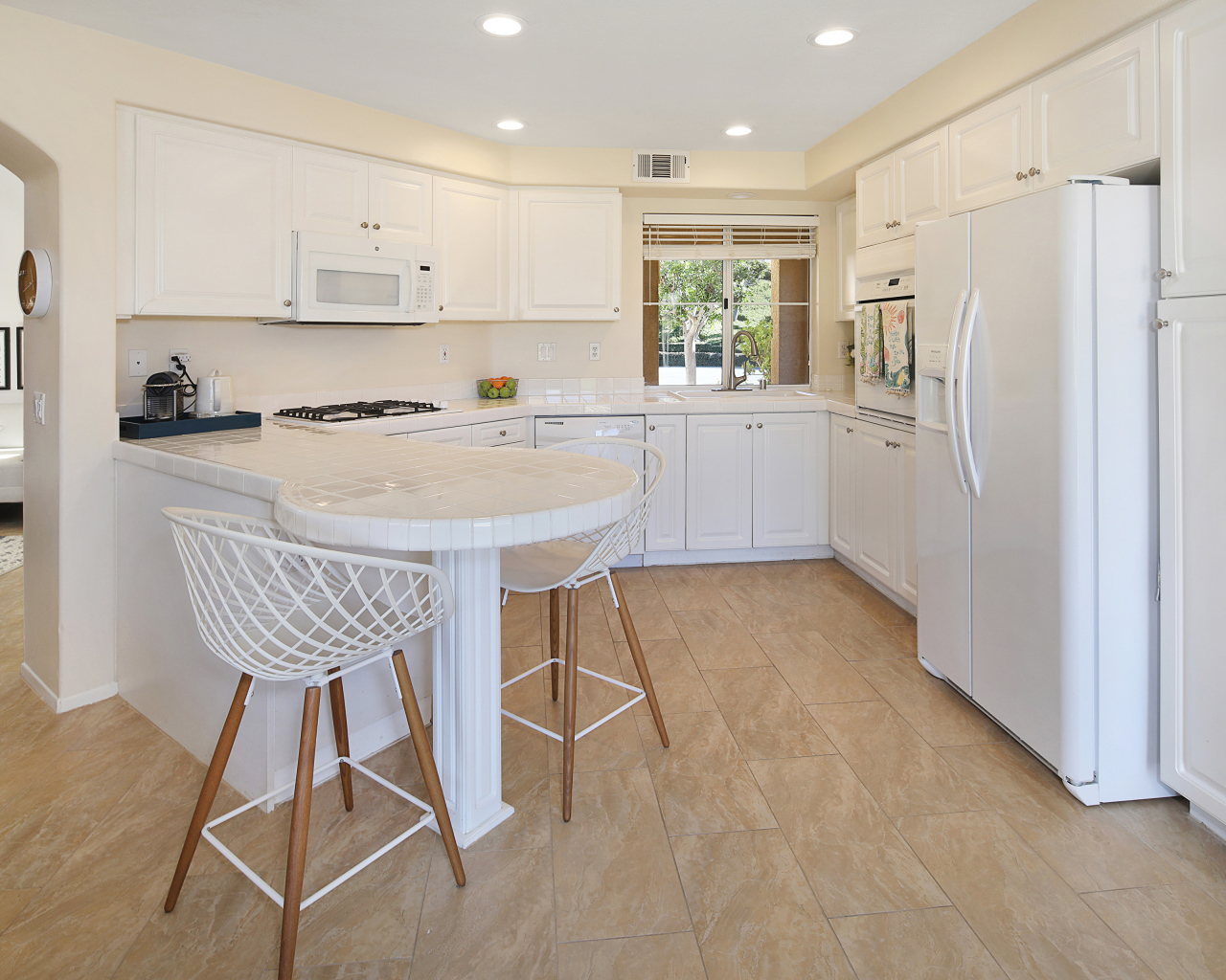 Большой холодильник и белая мебель на кухне 