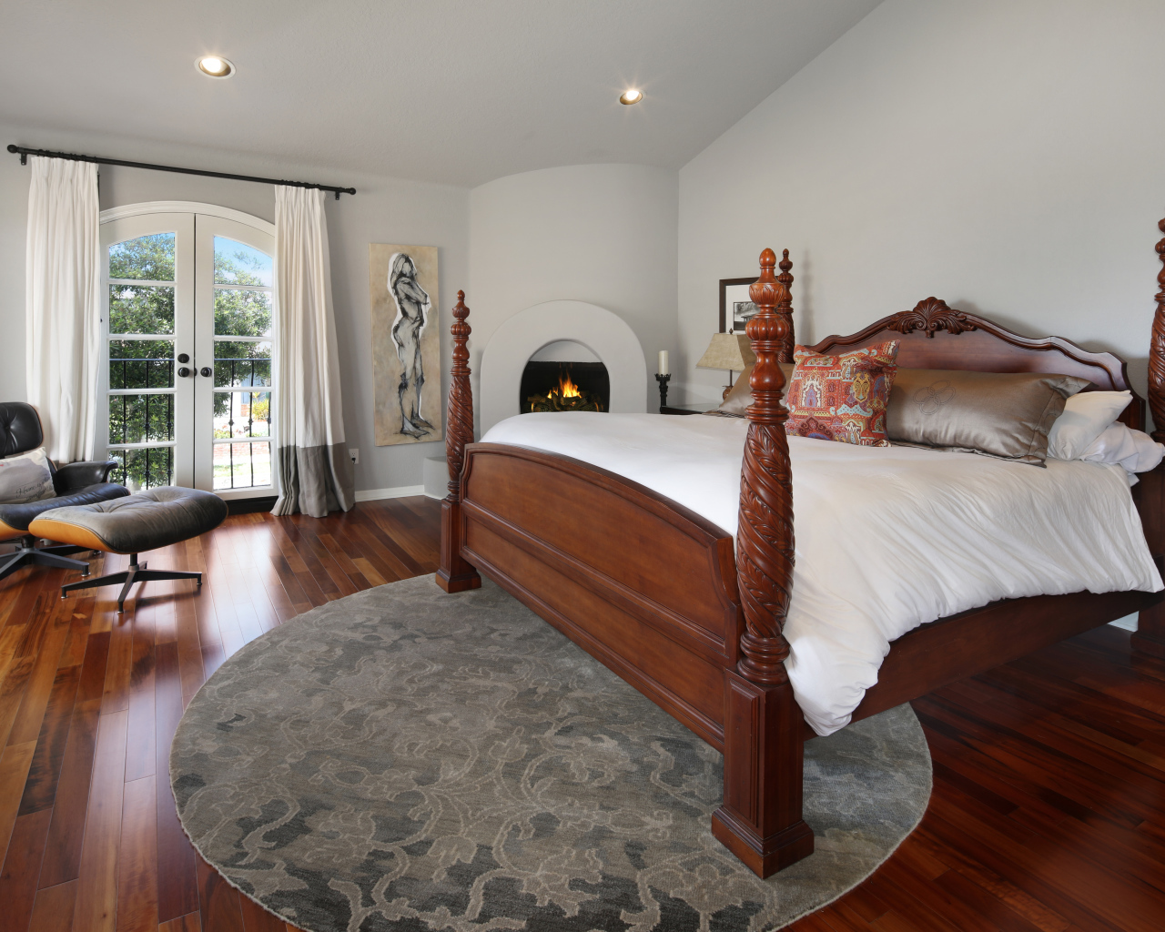 Большая деревянная кровать в спальне с камином 