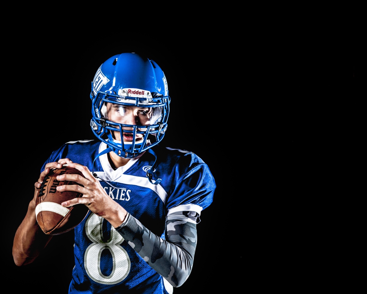 Мужчина игрок в американский футбол на черном фоне