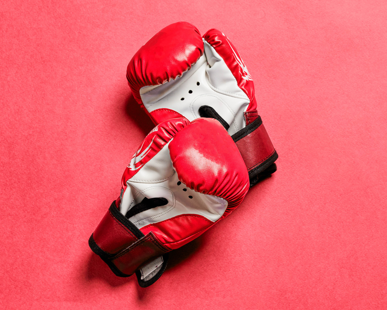 Красные боксерские перчатки на розовом фоне 