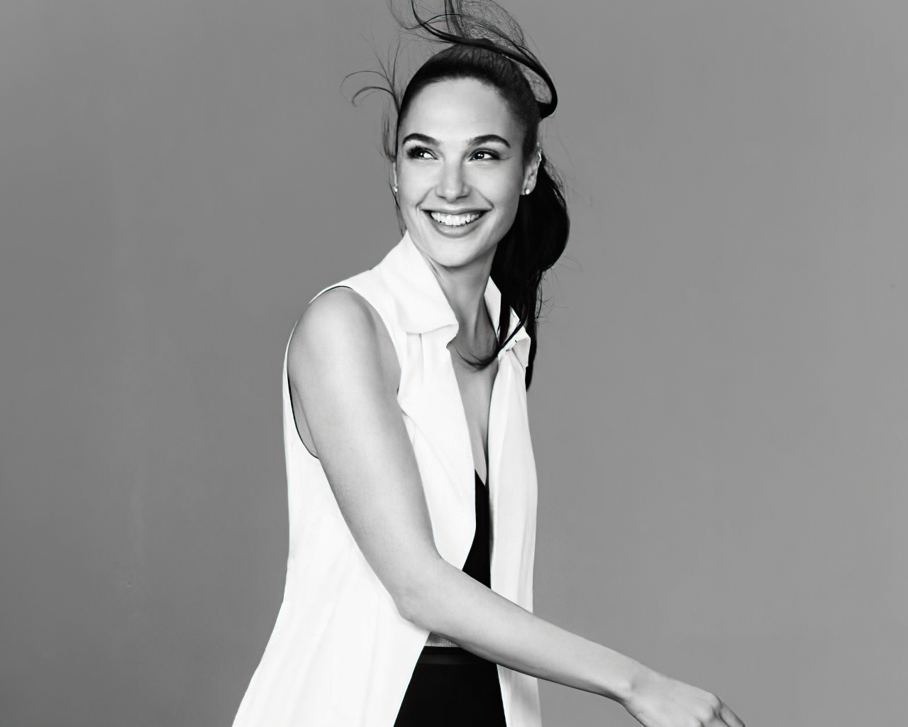 Улыбающаяся актриса Галь Гадот на сером фоне