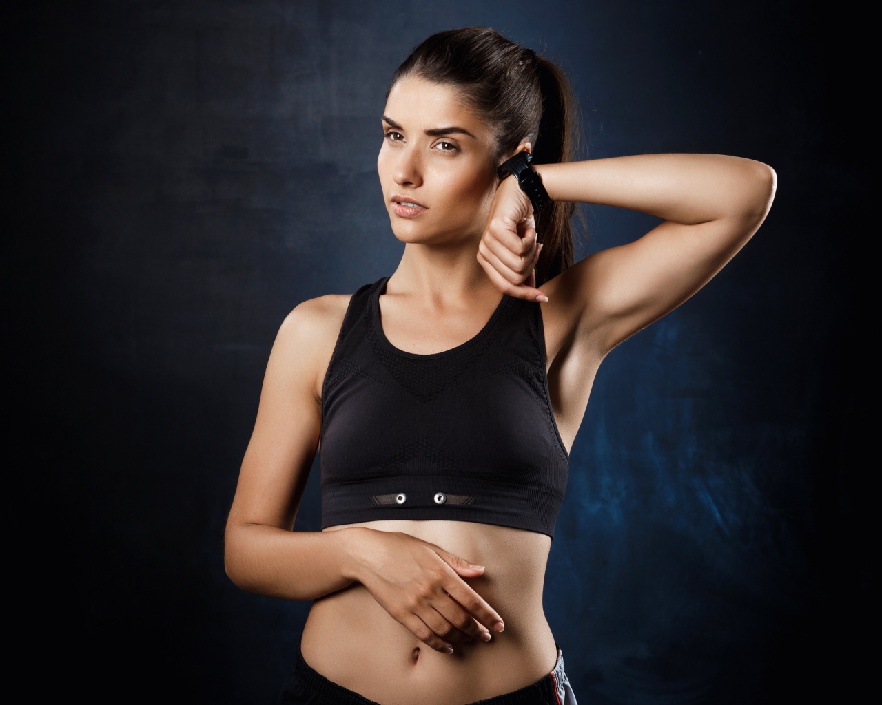 Спортивная девушка в черном топике с часами на руке 