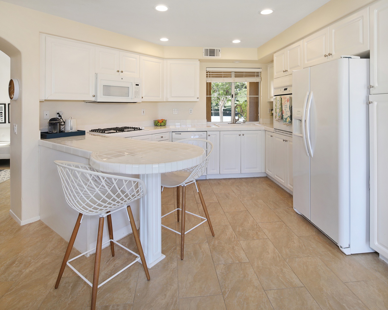 Белая стильная мебель с большим холодильником на кухне