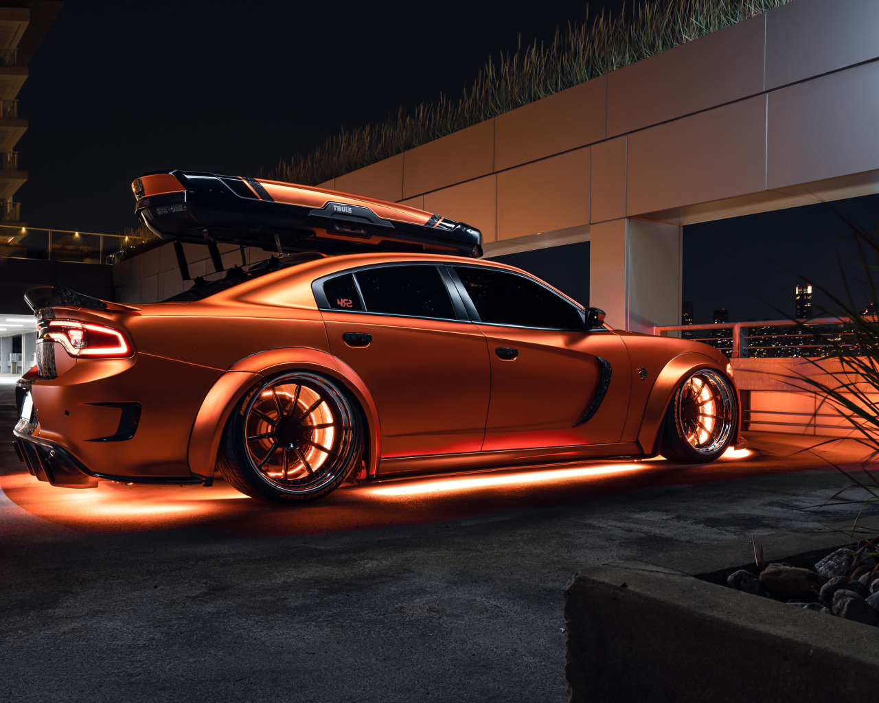 Оранжевый автомобиль Dodge Charger стоит у гаража