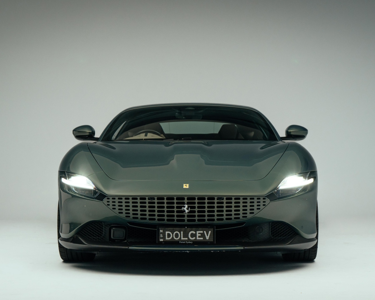 Автомобиль Ferrari Roma на сером фоне вид спереди