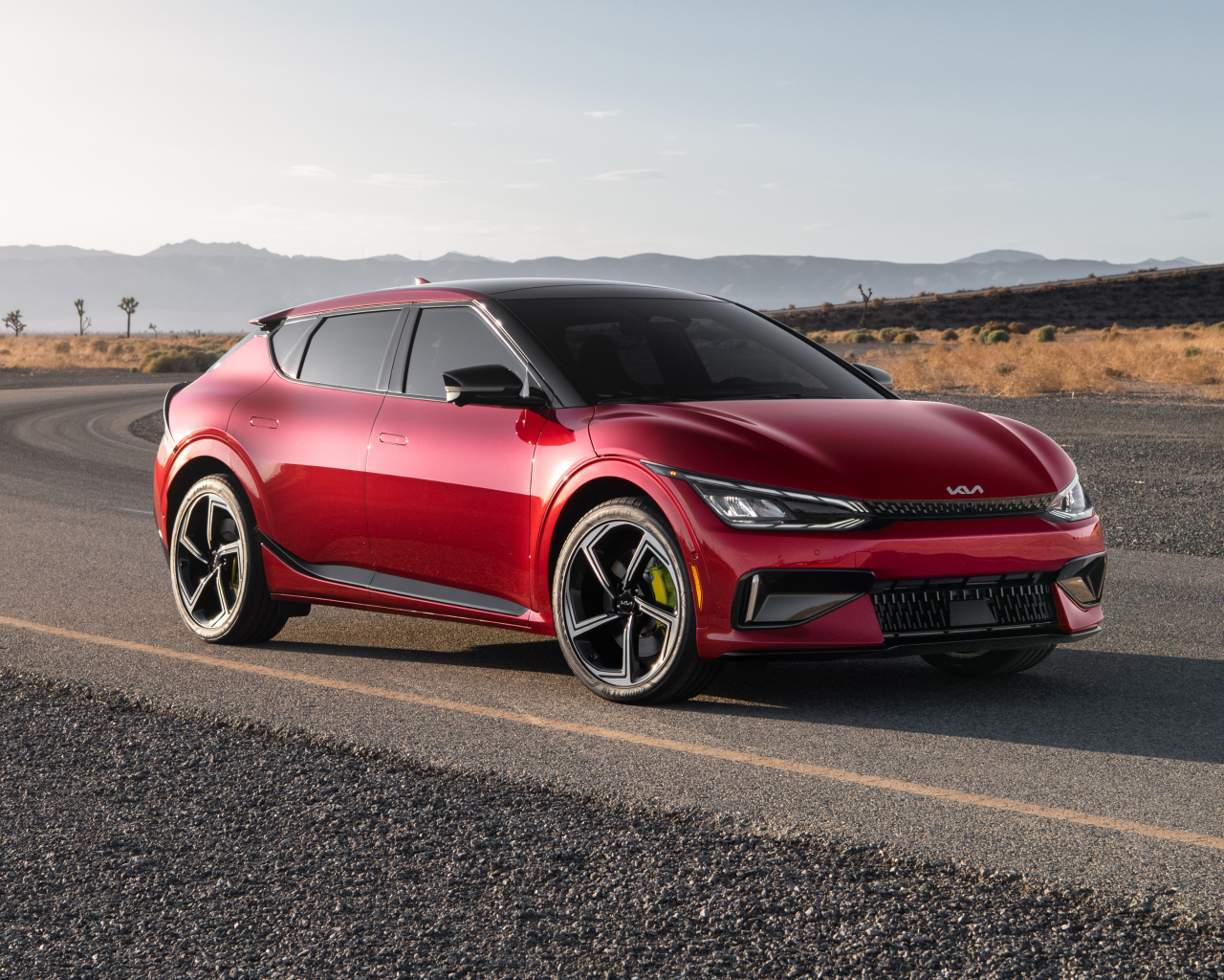 Красный автомобиль Kia EV6 GT 2023  года на дороге