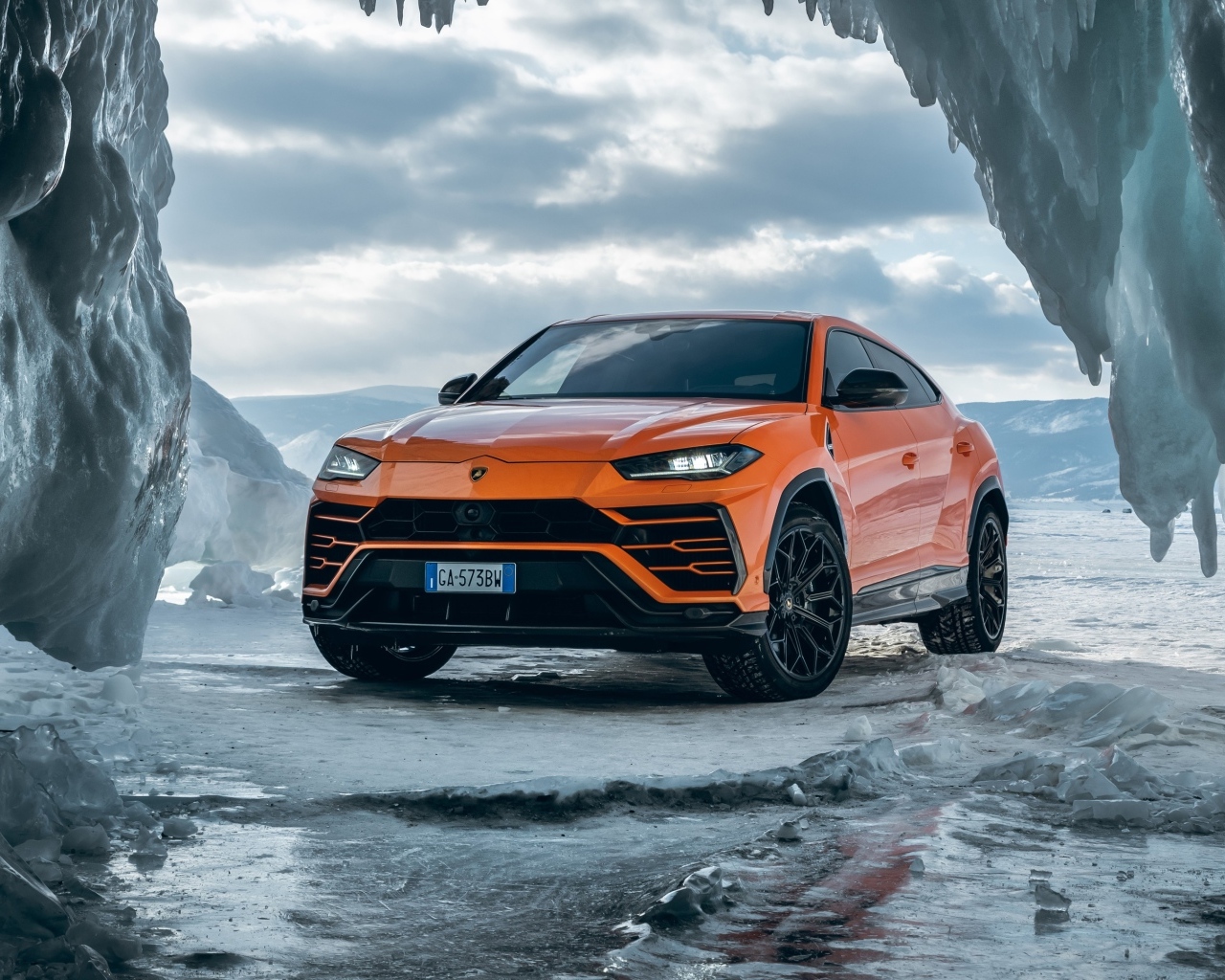 Оранжевый внедорожник Lamborghini Urus у ледяной пещеры