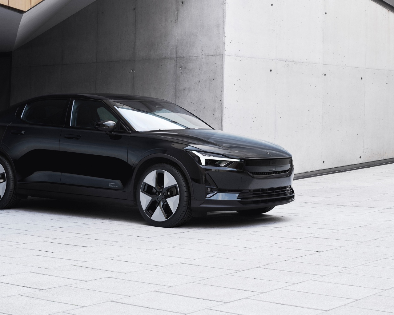 Черный автомобиль Polestar 2 2023 года у серой стены