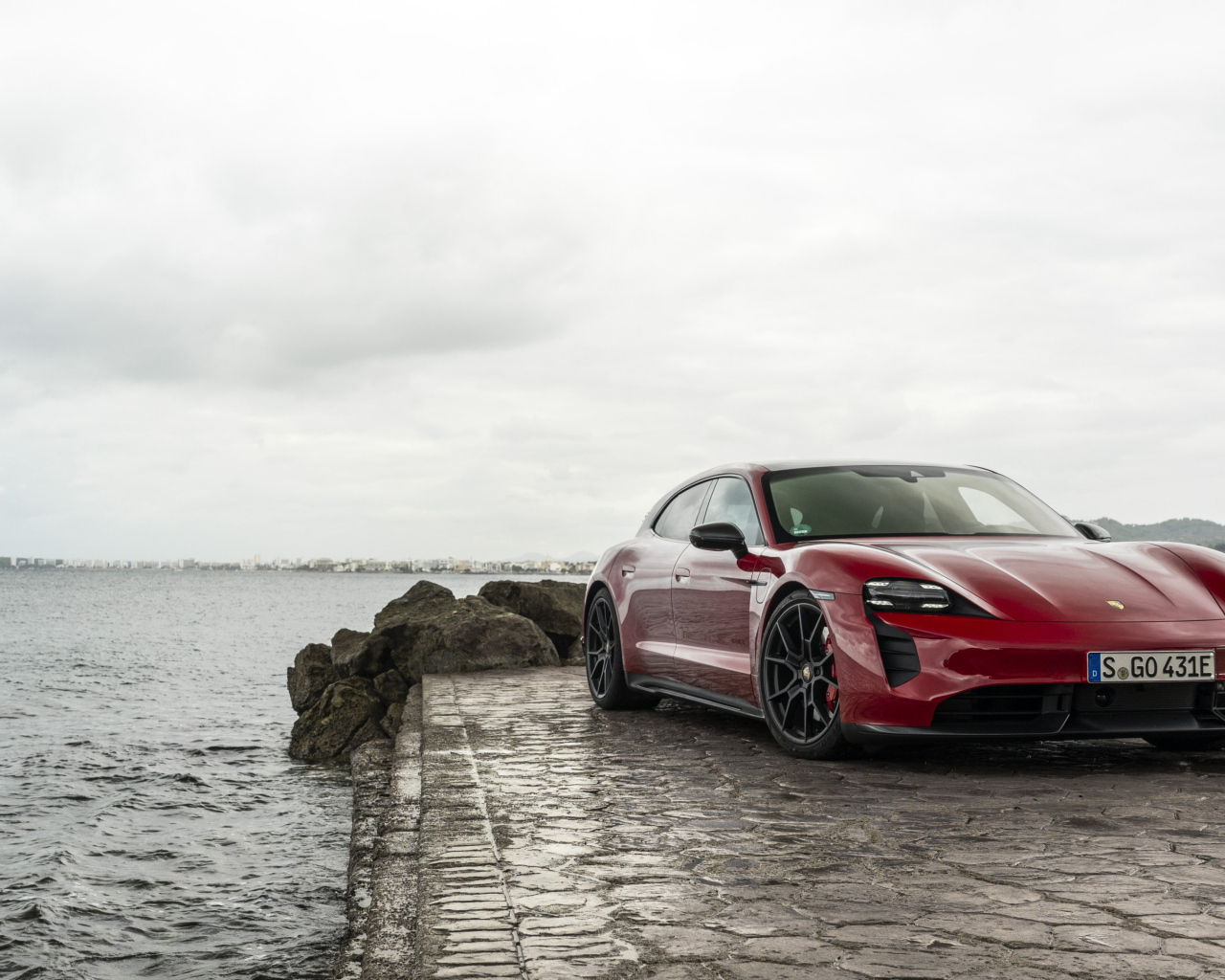 Красный автомобиль Porsche Taycan  у воды