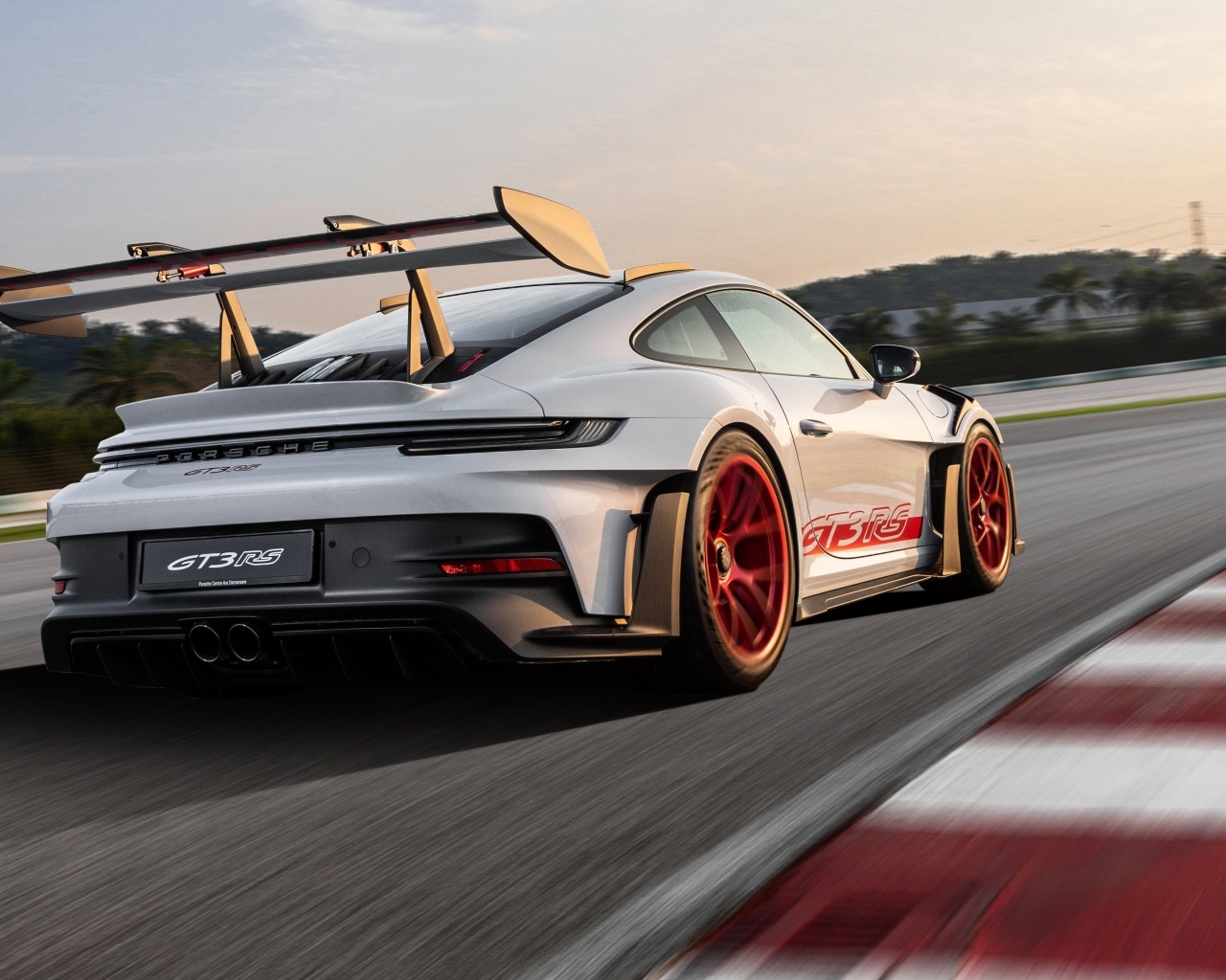 Серебристый спортивный автомобиль Porsche 911 GT3 RS Weissach Package 2023 года на трассе