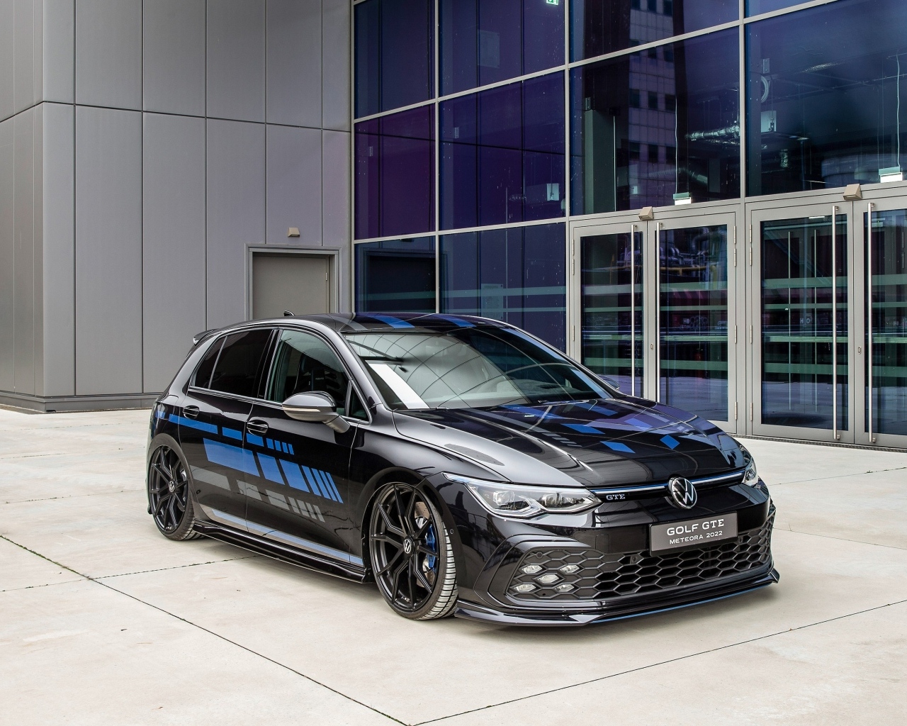 Черный автомобиль Volkswagen Golf GTE Meteora  у здания