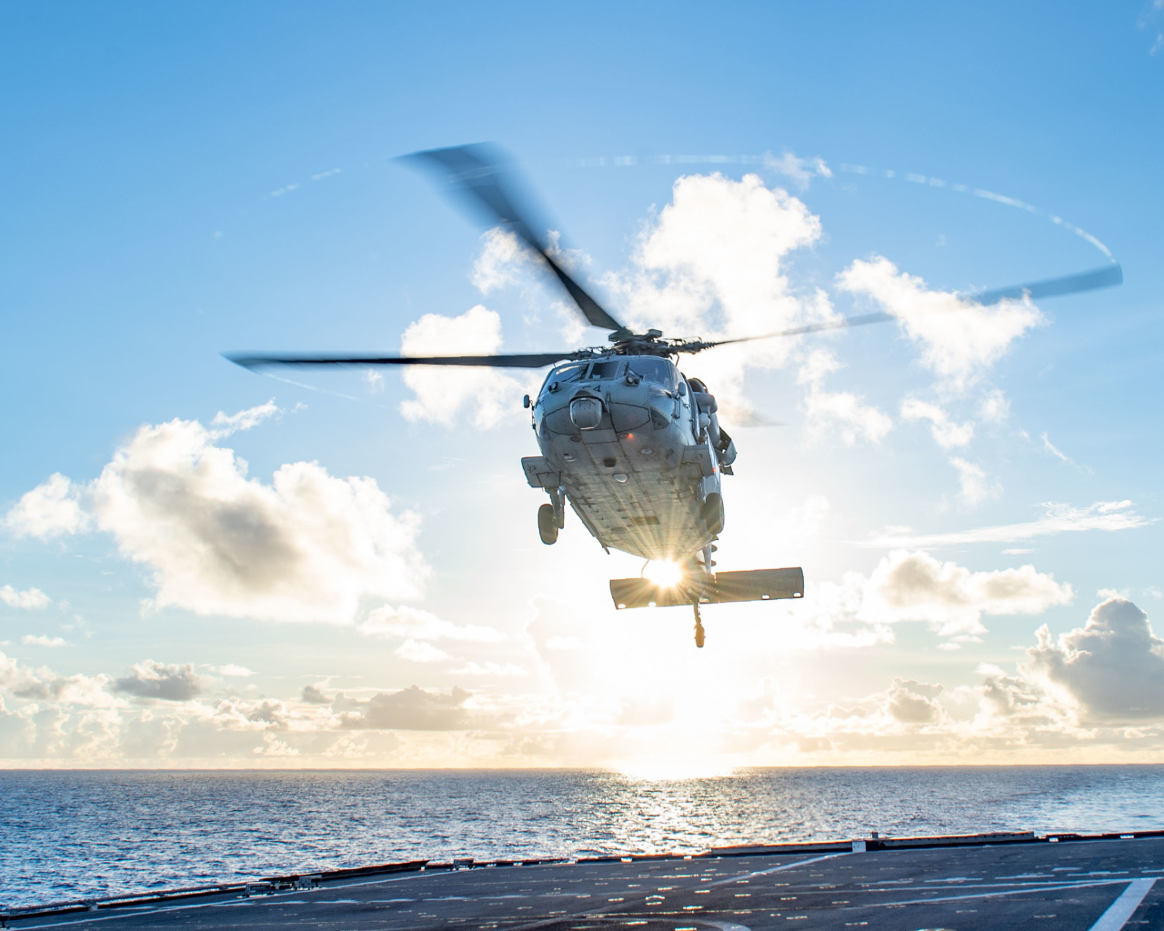 Военный вертолет приземляется на корабль в море
