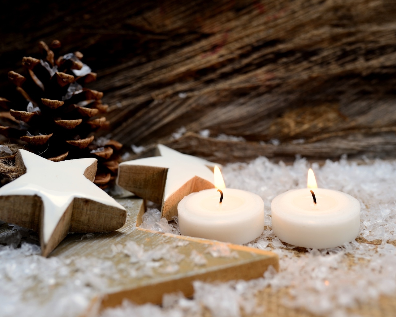 Две зажженные свечи, шишки и звезды