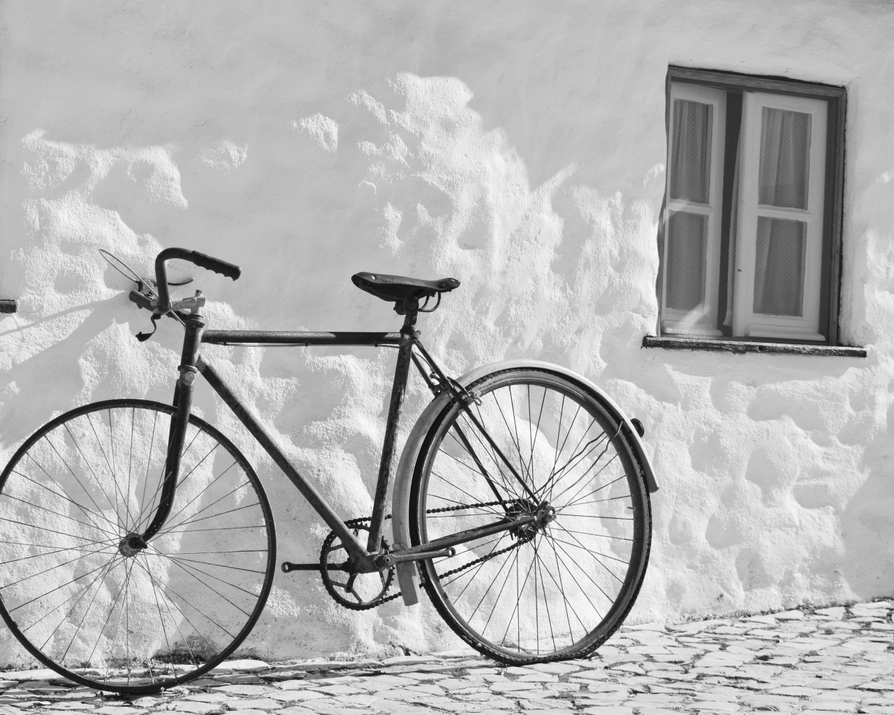 Черный велосипед стоит у белой стены