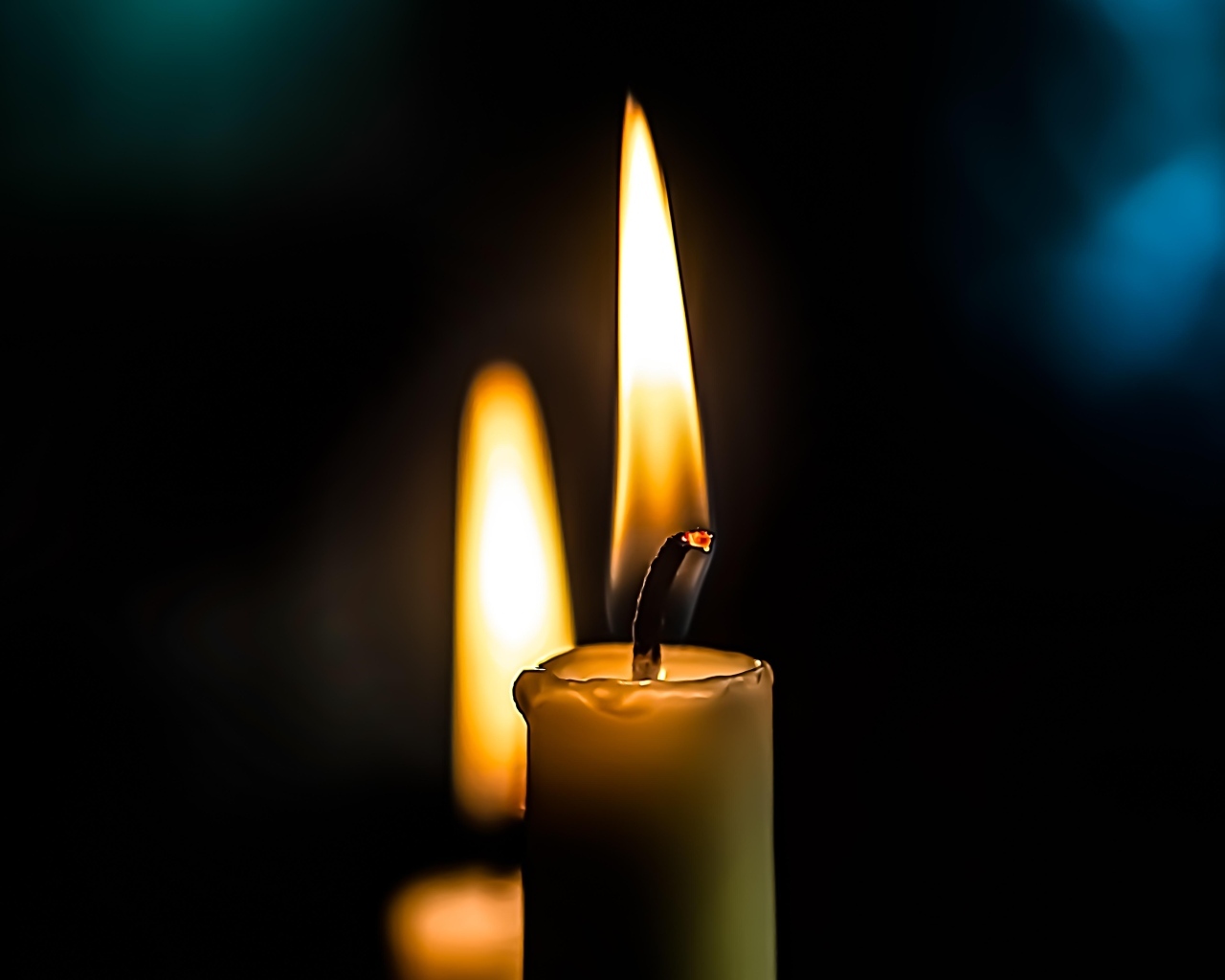 Зажженная свеча на черном фоне