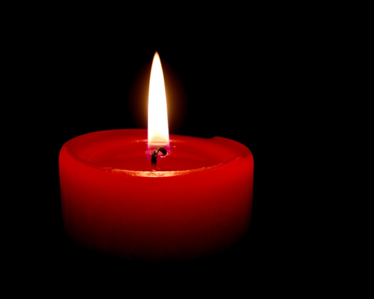 Зажженная красная свеча на черном фоне