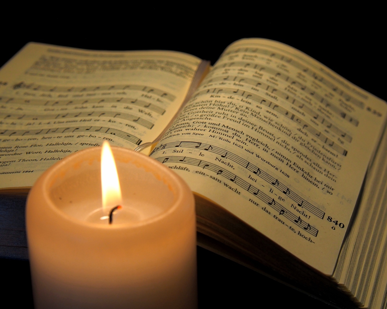 Зажженная свеча с книгой с нотами