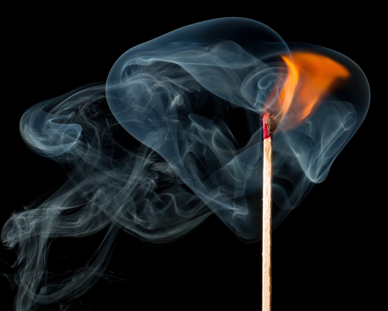 Зажженная спичка с дымом на черном фоне