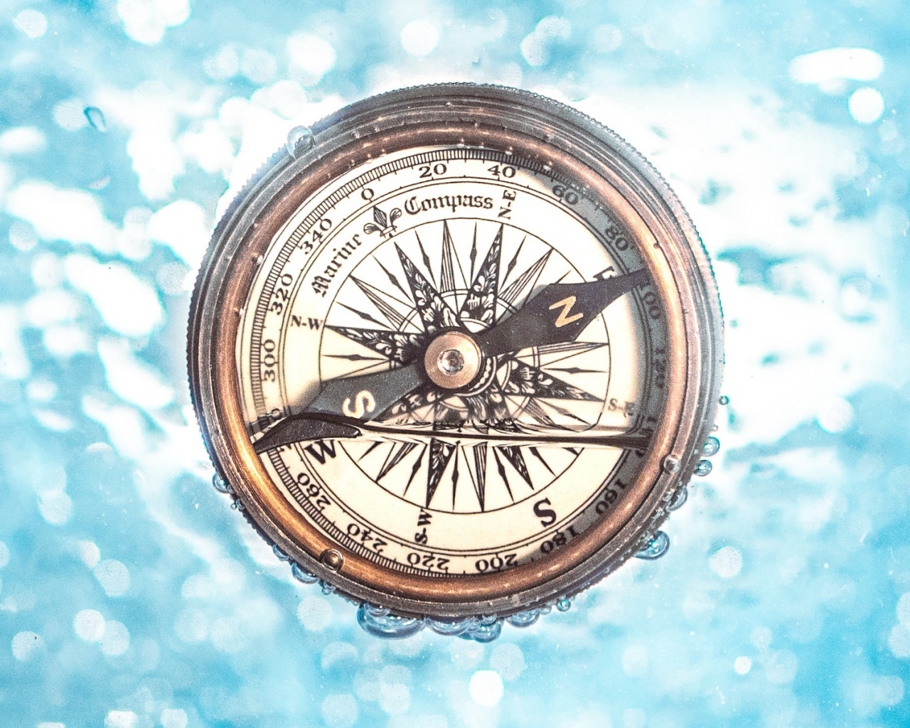 Старый компас в воде на голубом фоне