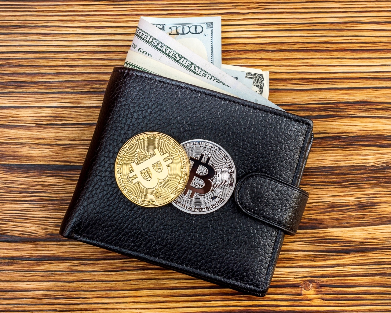 Черный кожаный кошелек с долларами и монетами биткоин