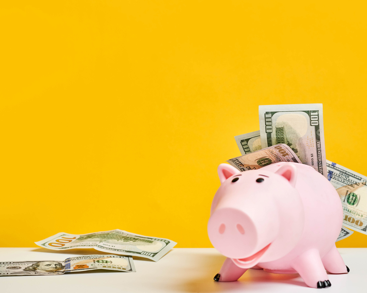 Pink pig piggy bank with banknotes on a yellow background